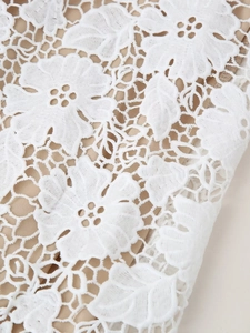 Détail du tissu en dentelle florale blanche avec doublure beige sur une robe de soirée