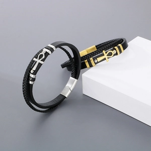 Detail of layered braided leather bracelets with silver and gold Ankh cross charms