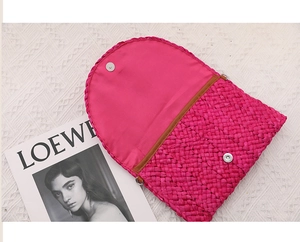 Dettaglio della borsa in paglia intrecciata rosa vivace con chiusura magnetica