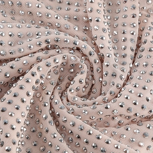 Gros plan de strass argentés sur tulle nude montrant la texture brillante du tissu