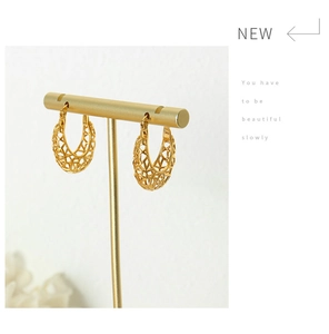 Close-up of gold hollow mesh U-shape hoop earrings on a minimalist display stand