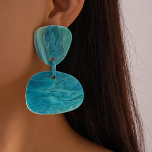 Close-up of model wearing teal resin geometric earrings with marble texture detail