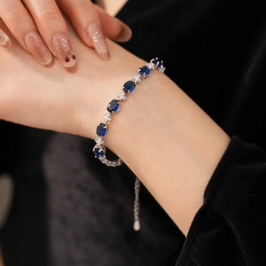 Macro shot of a silver bracelet with deep blue oval zircons on a woman's wrist