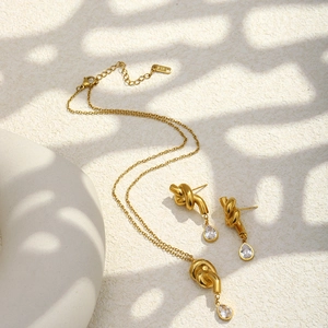 Detail of 18K gold-plated jewelry set with knot design and pear-cut zircon stones