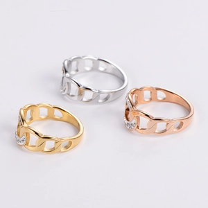 Hollow chain rings in gold, silver, and rose gold with pavé set crystals on a grey base