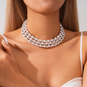 Detailed view of triple-layer pearl and rhinestone choker necklace on a model's neck