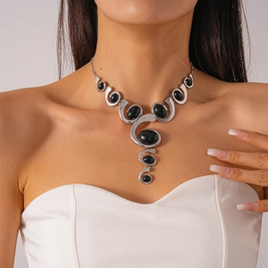 Détail d'un pendentif ovale en pierre noire sur un collier géométrique argenté