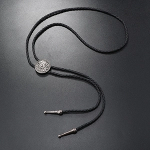 Close-up of vintage engraved silver bolo tie buckle on black braided leather cord