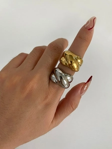 Detailed view of wide twisted wave rings in polished gold and silver on fingers