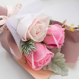 Close-up of mini soap flower bouquet with pink and white roses in delicate mesh wrap
