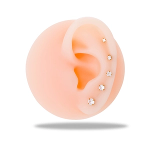 Par de pendientes de acero dorado con circonitas redondas claras en un modelo de oreja de silicona