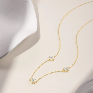 Detailed close-up of gold-plated five-petal flower pendants with sparkling zircons