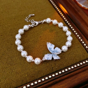 Détail du bracelet en perles avec papillon en cristal bleu sur tissu vert olive