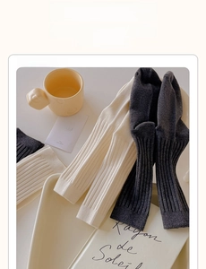 Detail shot of ivory and dark grey ribbed knit crew socks on a minimalist tray