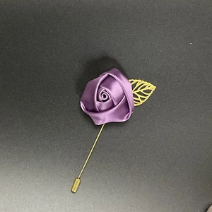 Detailed shot of purple satin rose brooch with golden hollow leaf on long needle pin