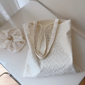 Detailed macro view of white floral lace embroidery on cotton tote bag with hair scrunchie