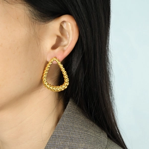Twisted gold geometric drop earrings for women shown on model with striped texture