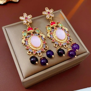 Detail of vintage palace style gold earrings with pink gemstones and colorful tassels