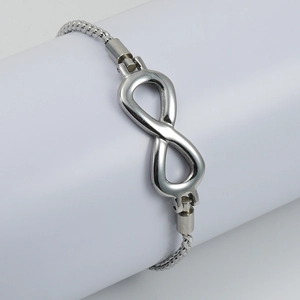 Minimalist silver infinity symbol steel bracelet with woven chain on a white pedestal