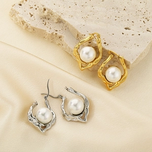 Detail view of gold and silver irregular textured earrings with pearls on silk cloth