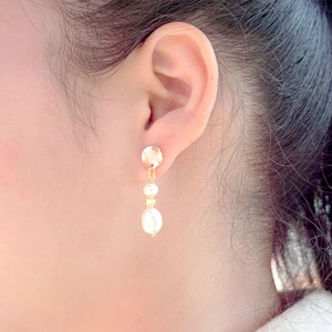 Elegant baroque pearl drop earrings in gold finish worn by a model for a chic look