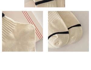 Close-up of cream striped cotton socks featuring ribbed texture and embroidery details