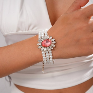 Detailed macro of a triple-layer pearl bracelet with a pink stone sunflower charm