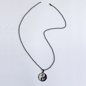 Macro view of yin yang pendant with floral engraving and black bead chain necklace