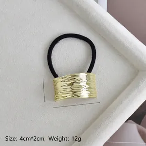 Close-up of golden alloy ponytail cuff with wavy texture and dimensions 4cm x 2cm