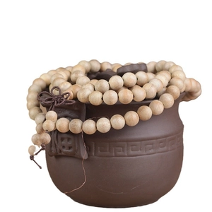 Bracelet de 108 perles en bois de camphrier naturel à côté d'un pot en céramique