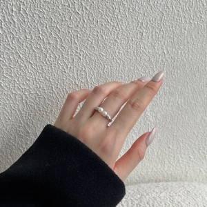Detail showing two white pearls on an adjustable silver ring band worn by a model