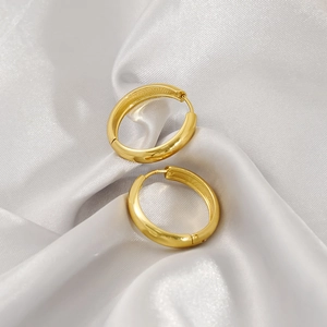 Elegant gold polished geometric U-shaped hoop earrings on white silk background