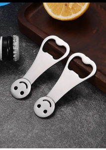 Detailed macro view of two stainless steel smile pattern bottle openers on a stone table