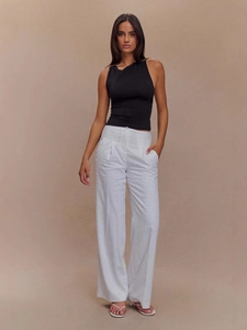 Top aderente smanicato con scollo a V e schiena scoperta con pantaloni bianchi larghi