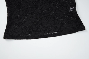 Détail du haut en dentelle noire montrant le motif floral et l'ourlet festonné