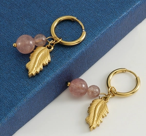 Detailed close-up of 18K gold-plated feather leaf earrings with natural purple stone beads