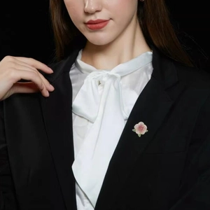 Exquisite camellia flower brooch with pink crystals and green leaves on black blazer