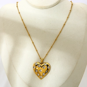 Macro detail of 18k gold plated heart pendant with inlaid sparkling white zircons