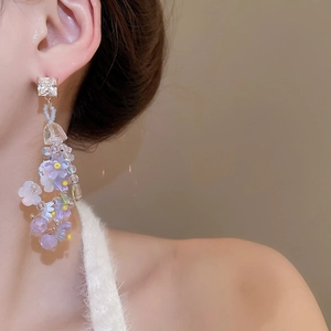 Detail of long floral tassel earrings featuring resin flowers and sparkling crystals