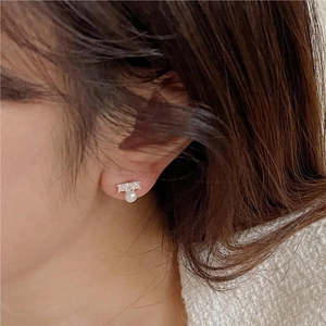 Close-up of a 925 sterling silver pearl earring with sparkling zircons on a model's ear