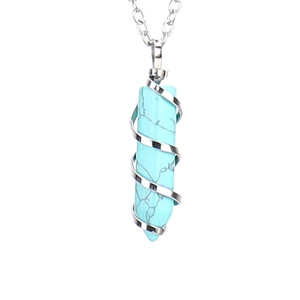 Macro view of a hexagonal turquoise crystal pendant with silver spiral wire on a chain