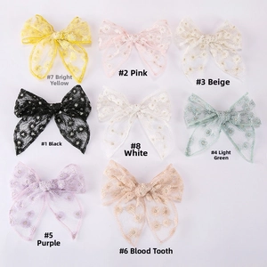 Flat lay of daisy embroidered tulle bow hair clips in eight different pastel colors