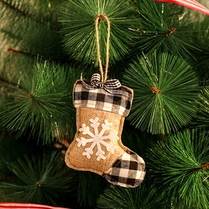 Détail de la chaussette de Noël en toile avec bordure à carreaux noirs et blancs sur pin