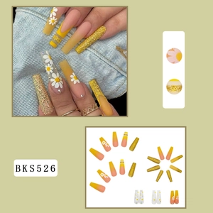 Detail of yellow gradient long ballerina nails with daisy motifs and gold glitter style