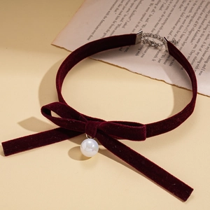Vintage wine red velvet bow choker necklace with a pearl pendant on retro book pages