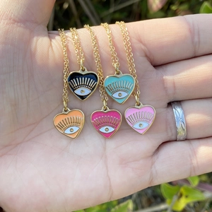 Hand holding five colorful enamel heart evil eye pendants on gold stainless steel chains