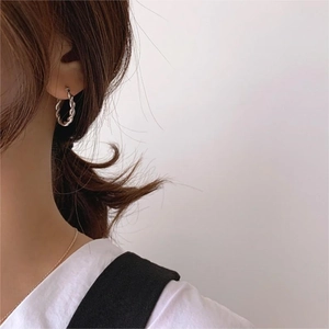 Elegant 925 sterling silver twisted hoop earrings worn by a model in a minimalist style