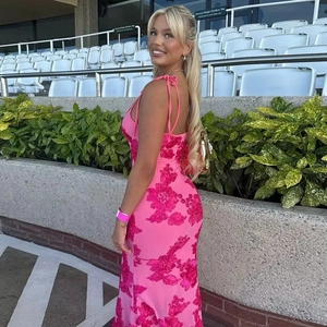 Side view of a slim pink bodycon dress with floral embroidery on stadium stands