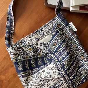 Detail of bohemian floral linen bag featuring paisley print and magnetic buckle