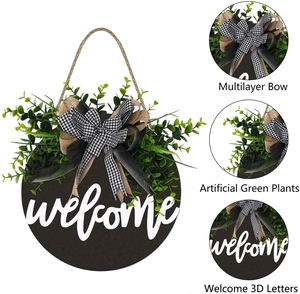 Detail of wooden welcome sign with 3D letters, lush faux greenery and burlap bow tie